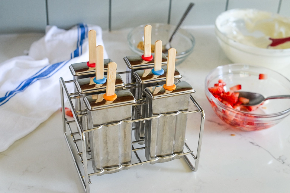 Stainless steel popsicle mold rack filled with yogurt mixture for Greek yogurt popsicles.