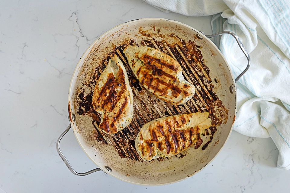 Grilled chicken breasts cooking in a skillet.
